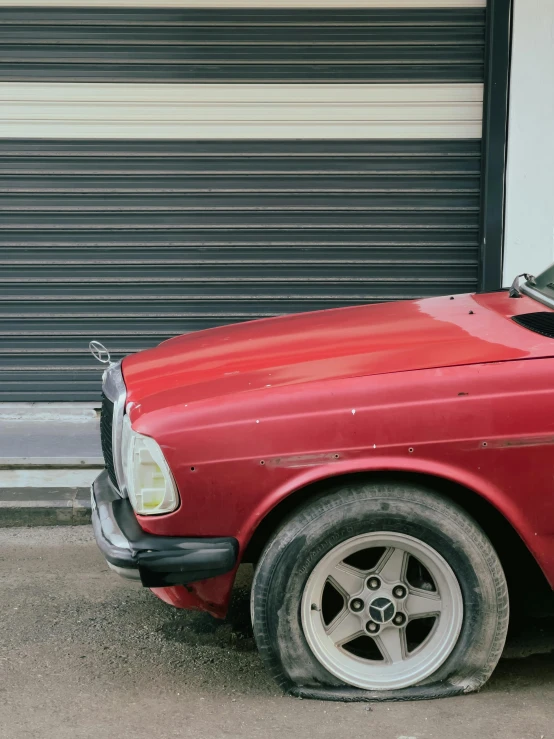 a close up of an older red sports car parked on a city street