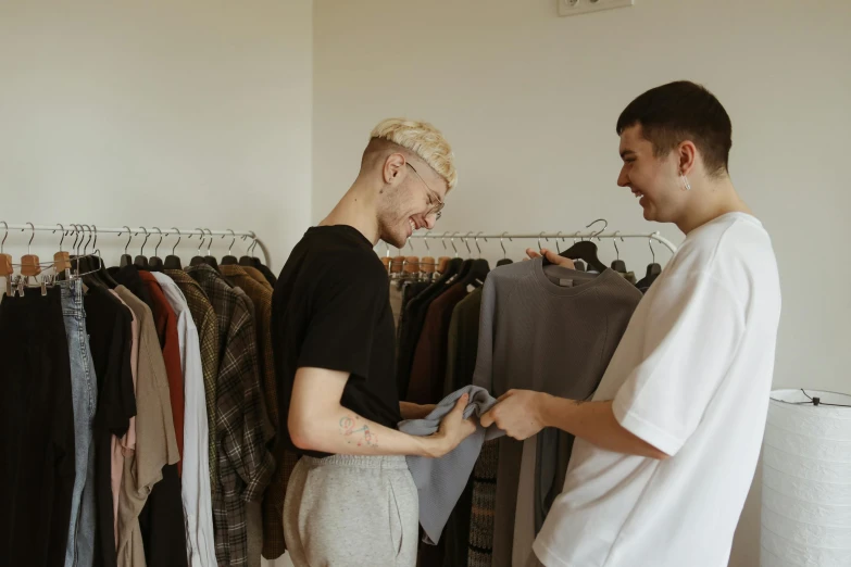 a man handing another mans shirt in the closet