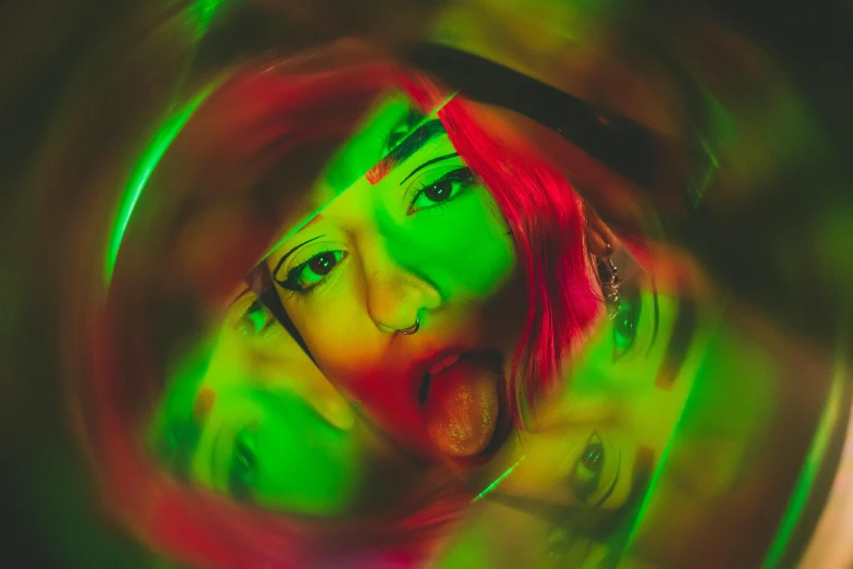 a woman in a multicolored pograph looks directly into a round mirror