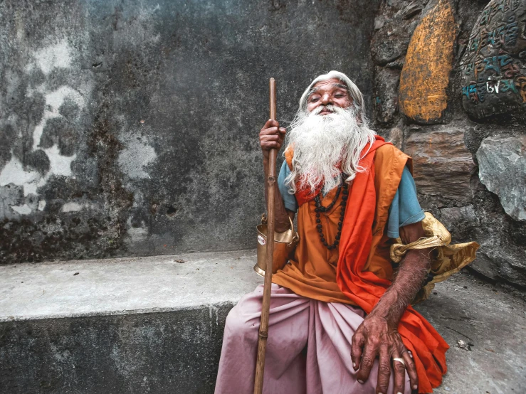 an old man with a long white beard and a white turban is sitting outside