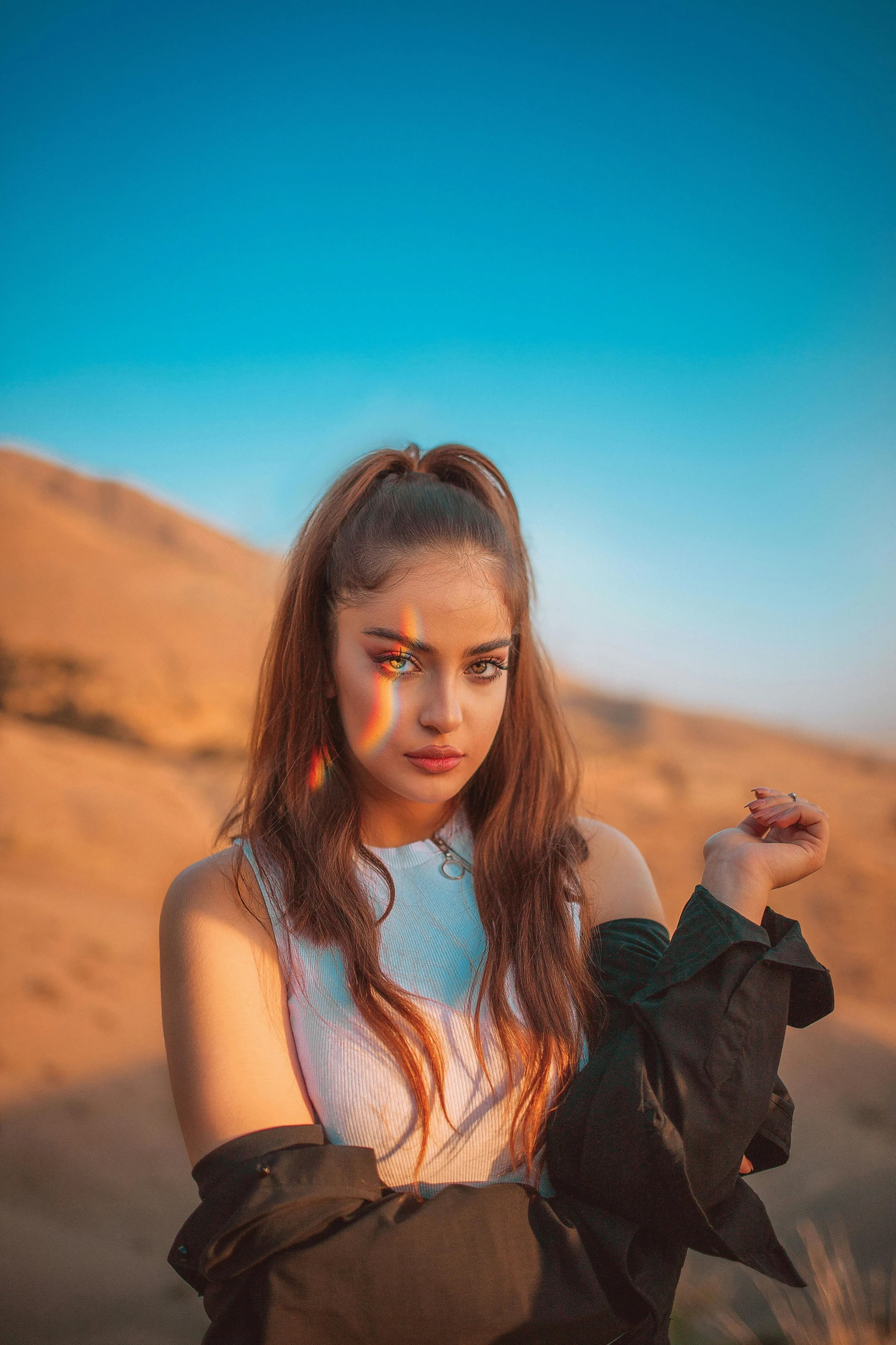 a woman holding a glove while sitting on top of a desert