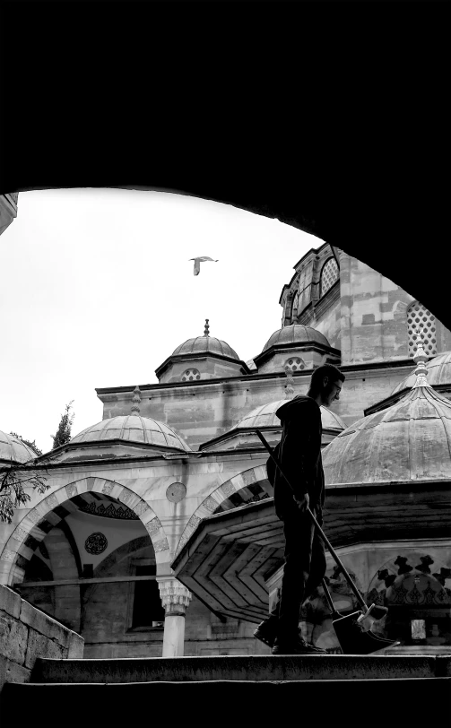 the silhouette of a man holding an umbrella looking at a tall building