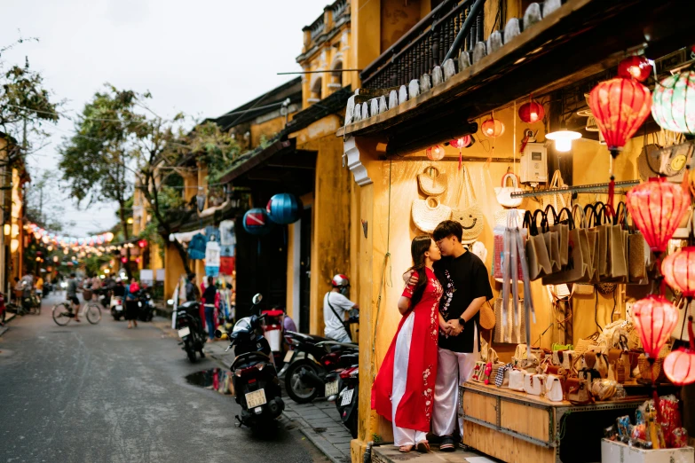 couple in traditional chinese attire kiss at the entrance of the shop