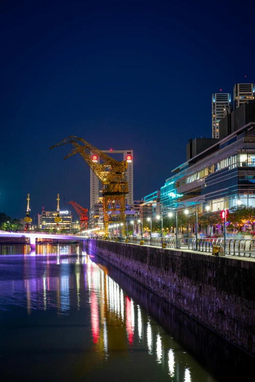 a river running beside a building and bridge at night