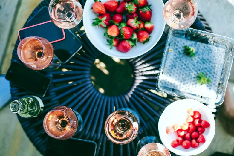 several glasses and plates sit on a table with strawberries on top