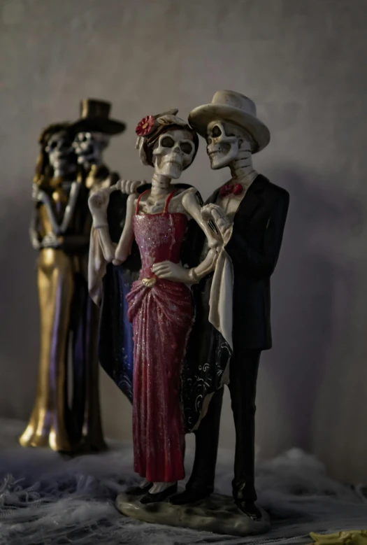 skeleton statues stand beside one another wearing dresses and hats