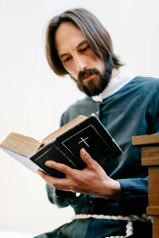 a man sitting on a chair while reading a bible