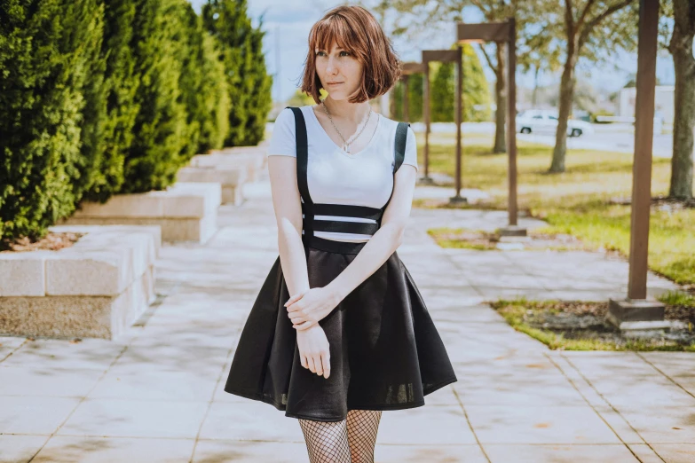 a person standing on a sidewalk with a very long black dress