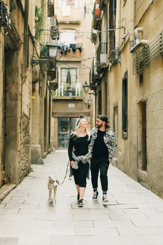 a man and woman walking down the street with their dog