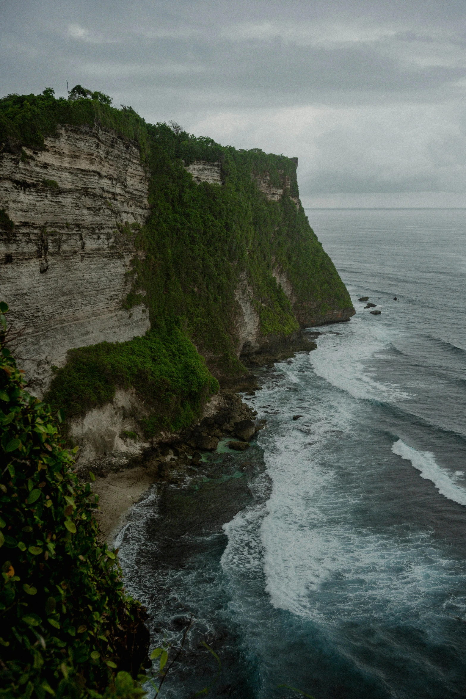 an airplane flies over a rugged cliff and ocean