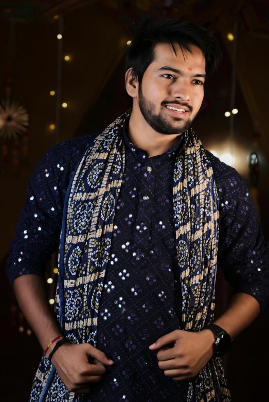 a man in blue shirt standing next to christmas lights