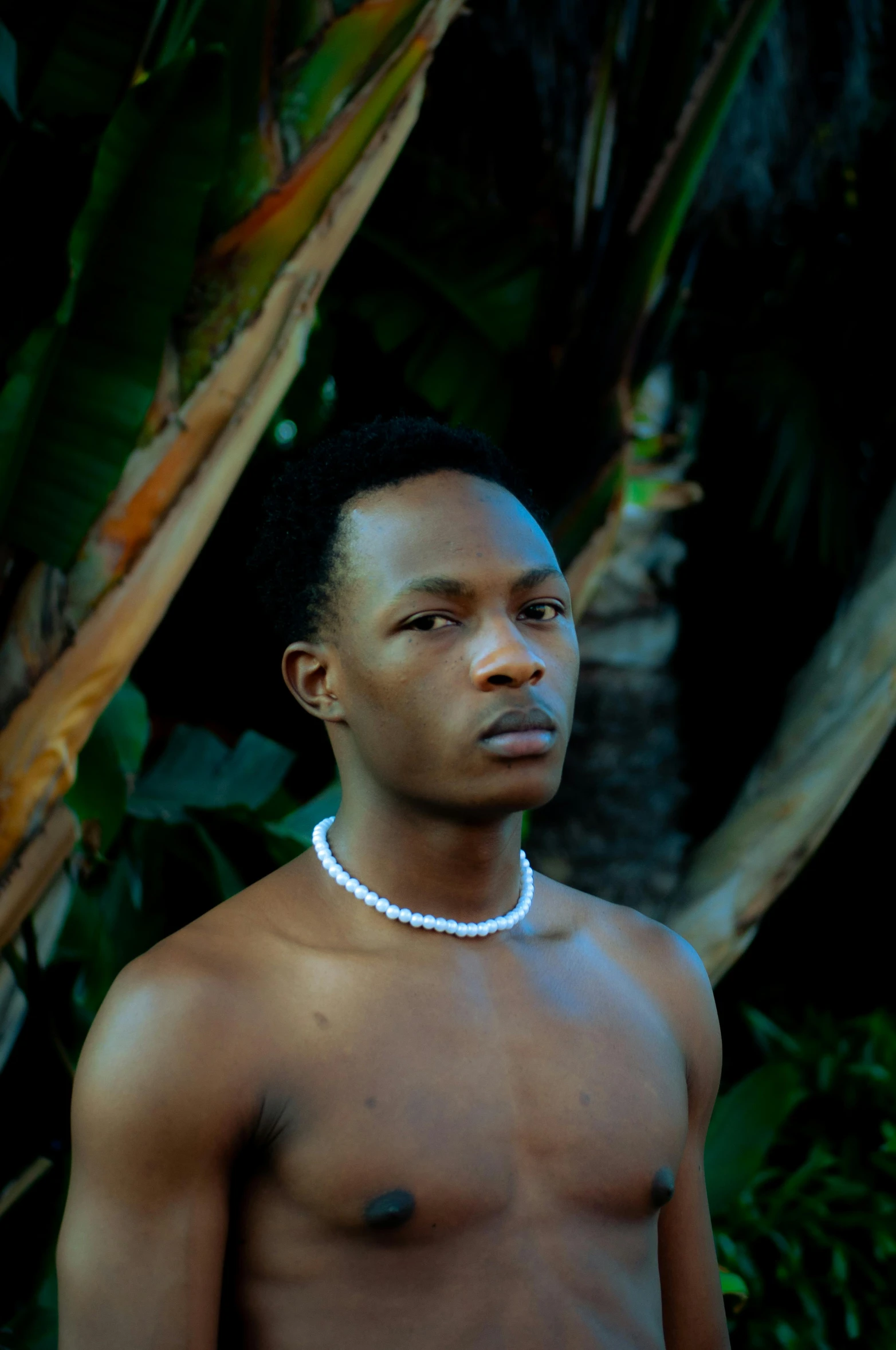 a man without a shirt standing next to a tree