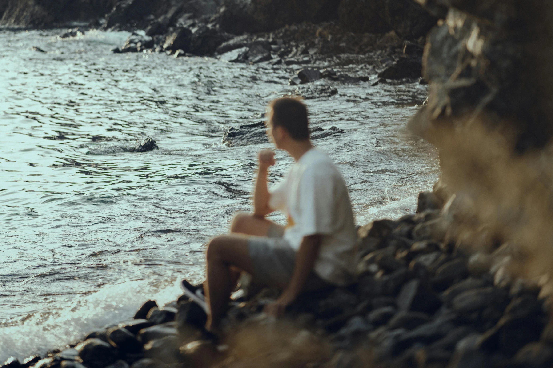 there is a young man that is sitting on the rocks and staring at soing