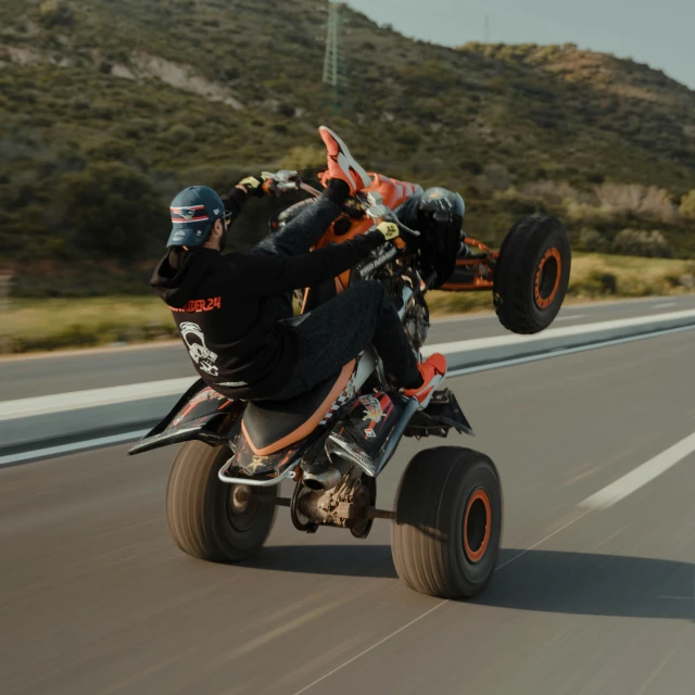 a person on a four wheeled vehicle rides down the road