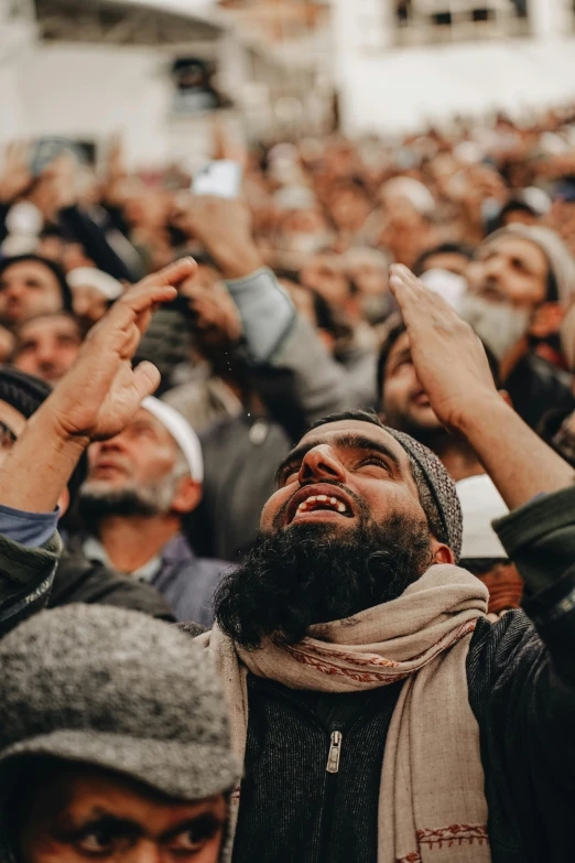 a crowd of people, mostly in winter clothing, one has his head tilted up