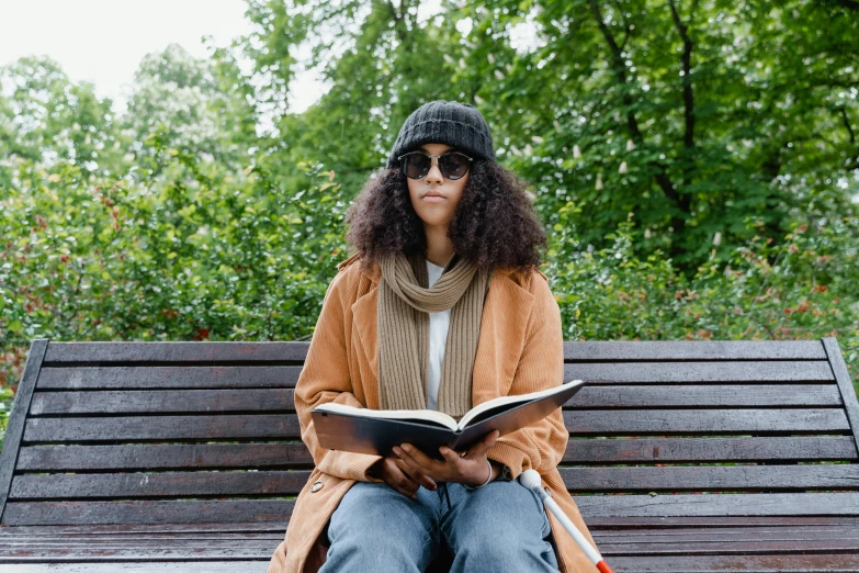 there is a person that is sitting on a bench reading a book