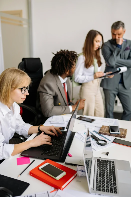 three people are in an office work space with the laptops open