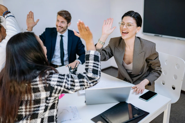 an office meeting with two women and a man giving a high five