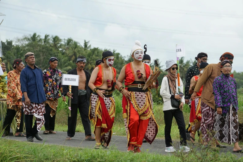 several men wearing colorful attire and hats stand in front of other people