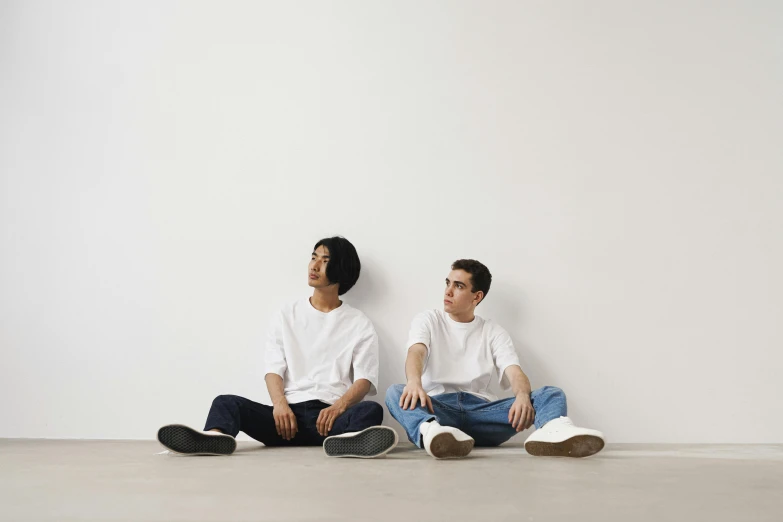 two young men sitting next to each other on the floor