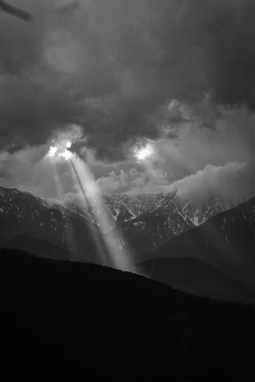 the sun shines through clouds over snow capped mountains