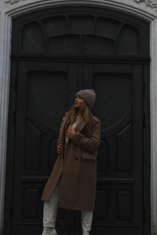 a woman is standing in front of a black door