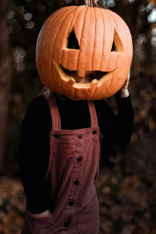 a person wearing an apron holding up a carved pumpkin