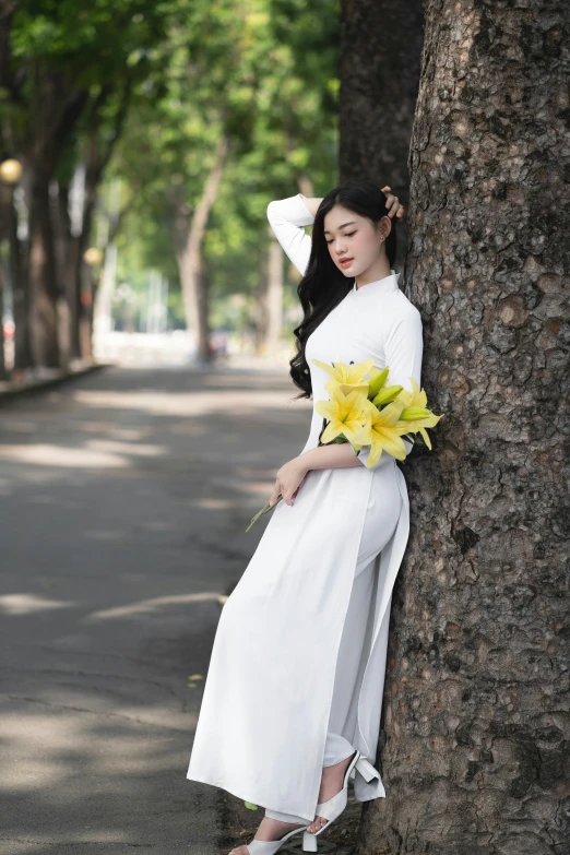 a woman poses while leaning against a tree