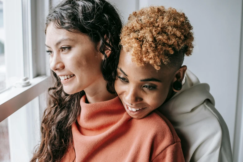 a couple of women sitting next to each other on a window sill