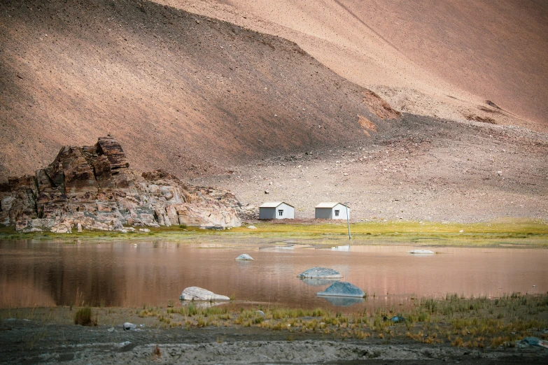 two boats sit in a still - calm lake with rocks and cliffs