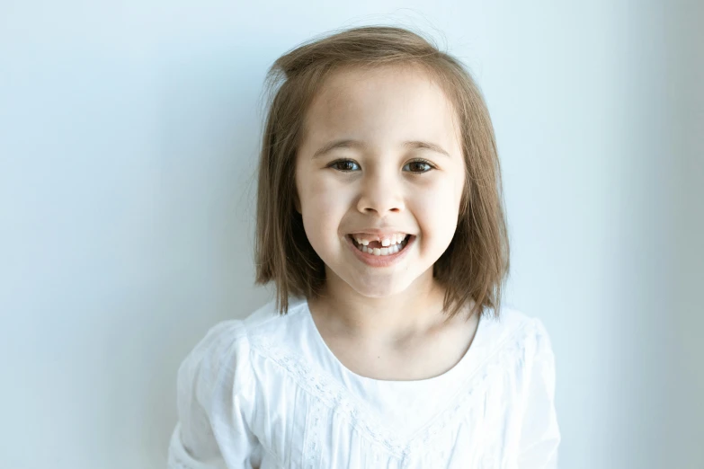 a girl with brown hair in front of a blue wall