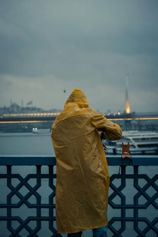 a person wearing a yellow rain coat next to a fence