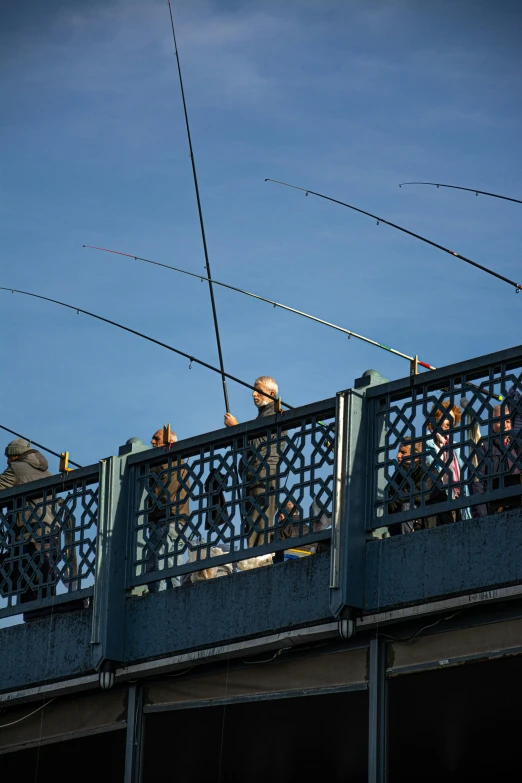 people are fishing on the bridge while one watches