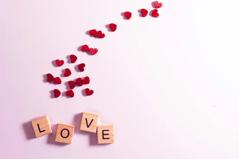 love spelled by scrabble on a white surface