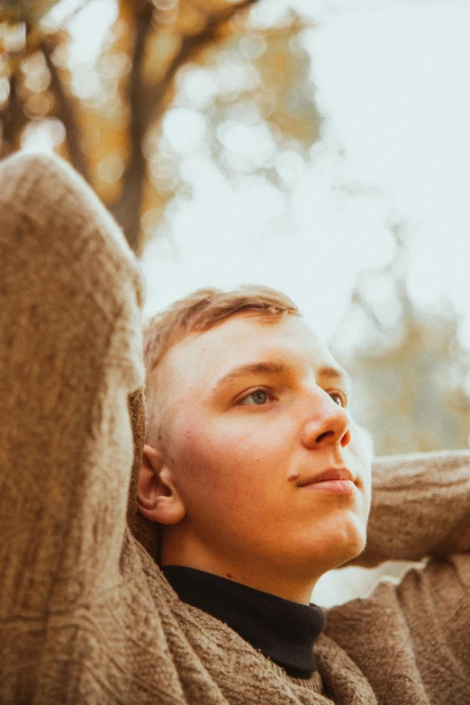 man with grey sweater posing for po near trees