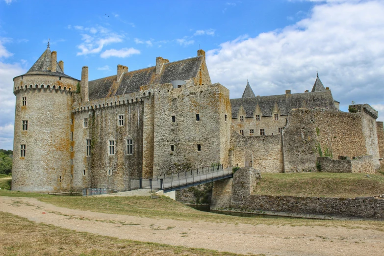 an old stone castle sits on a grassy hill