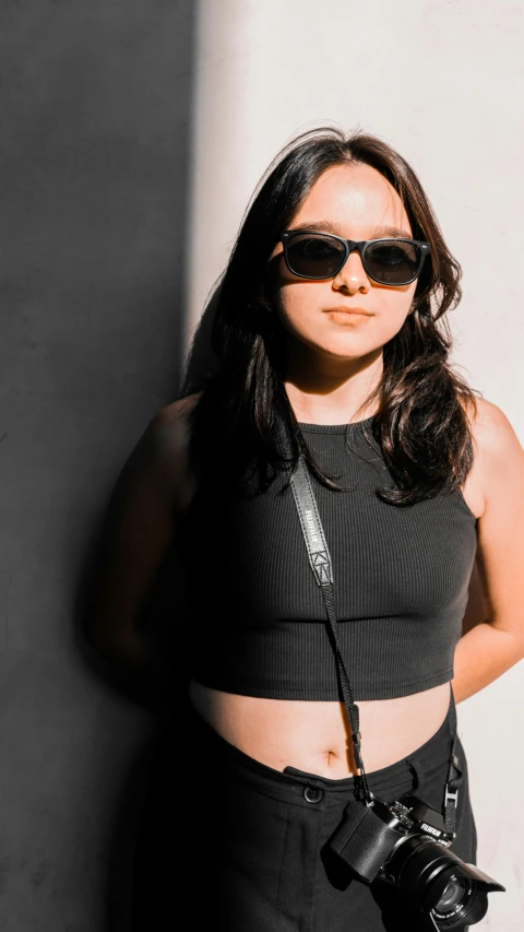 a woman leaning up against a wall wearing sunglasses