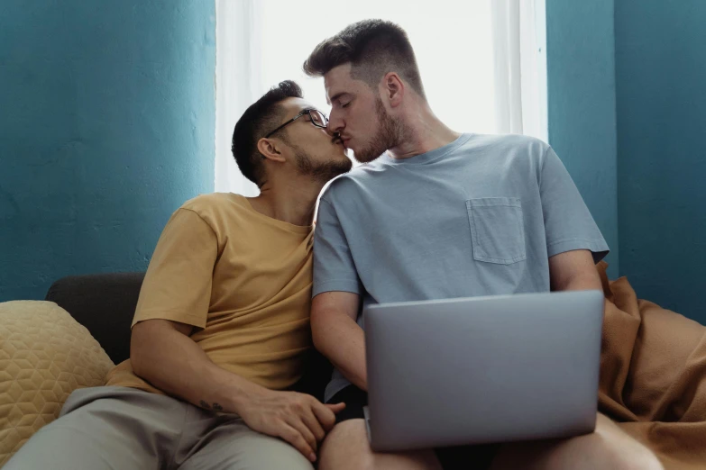 there are two men that are sharing a kiss over a laptop