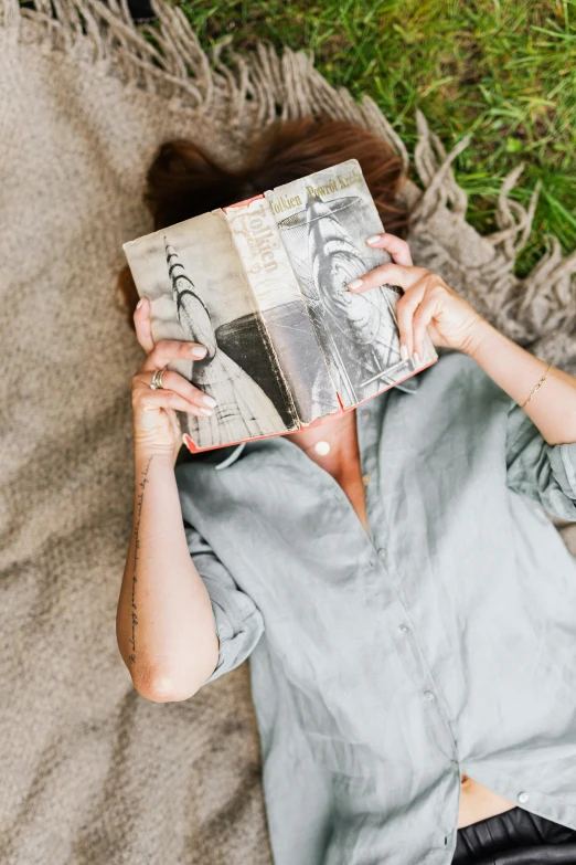 woman is laying down while reading the paper