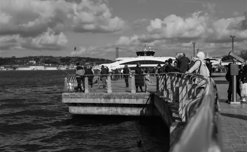 people stand on the pier as it looks like a boat is entering