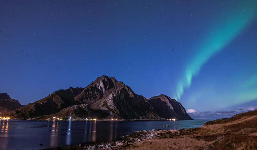 the aurora lights on the rocks are reflected in the water