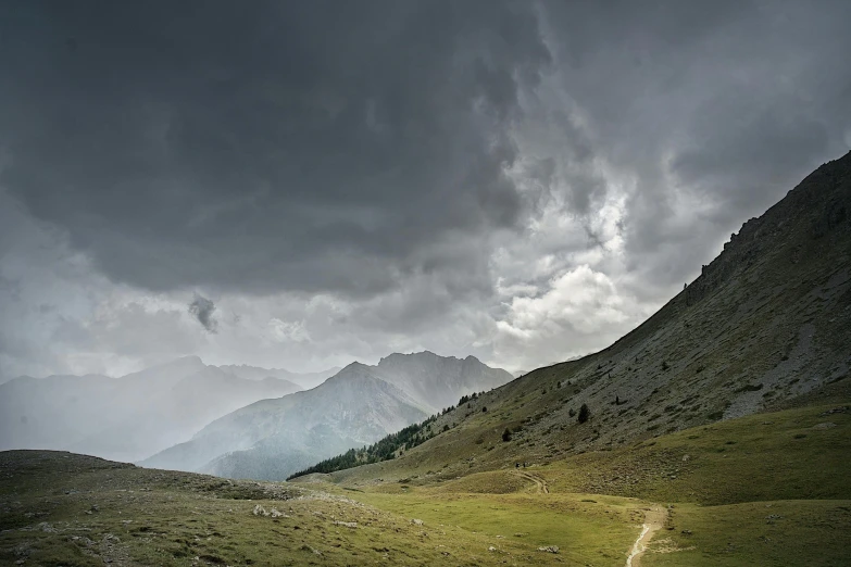 several mountains with some very dark clouds and some very green grass