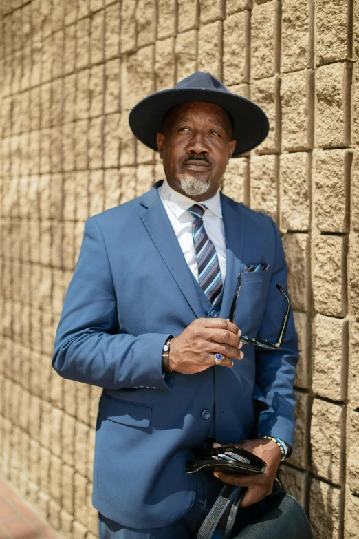 a man dressed up standing next to a brick wall