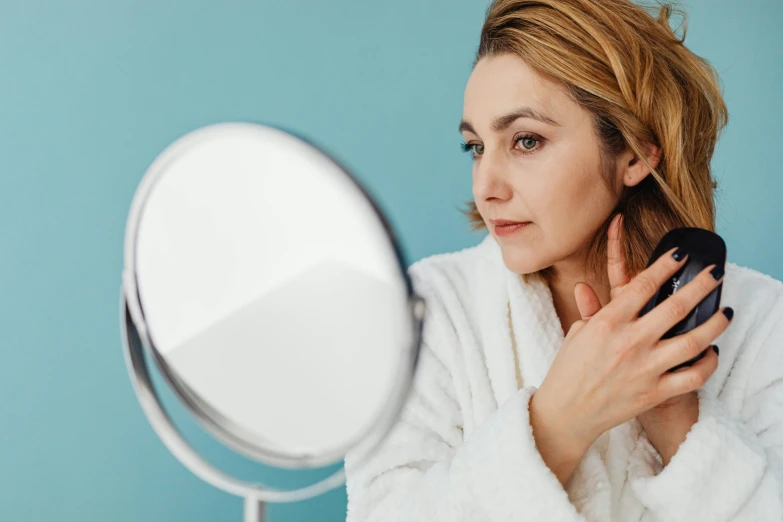 a woman in a white sweater putting on her hair with a blow dryer