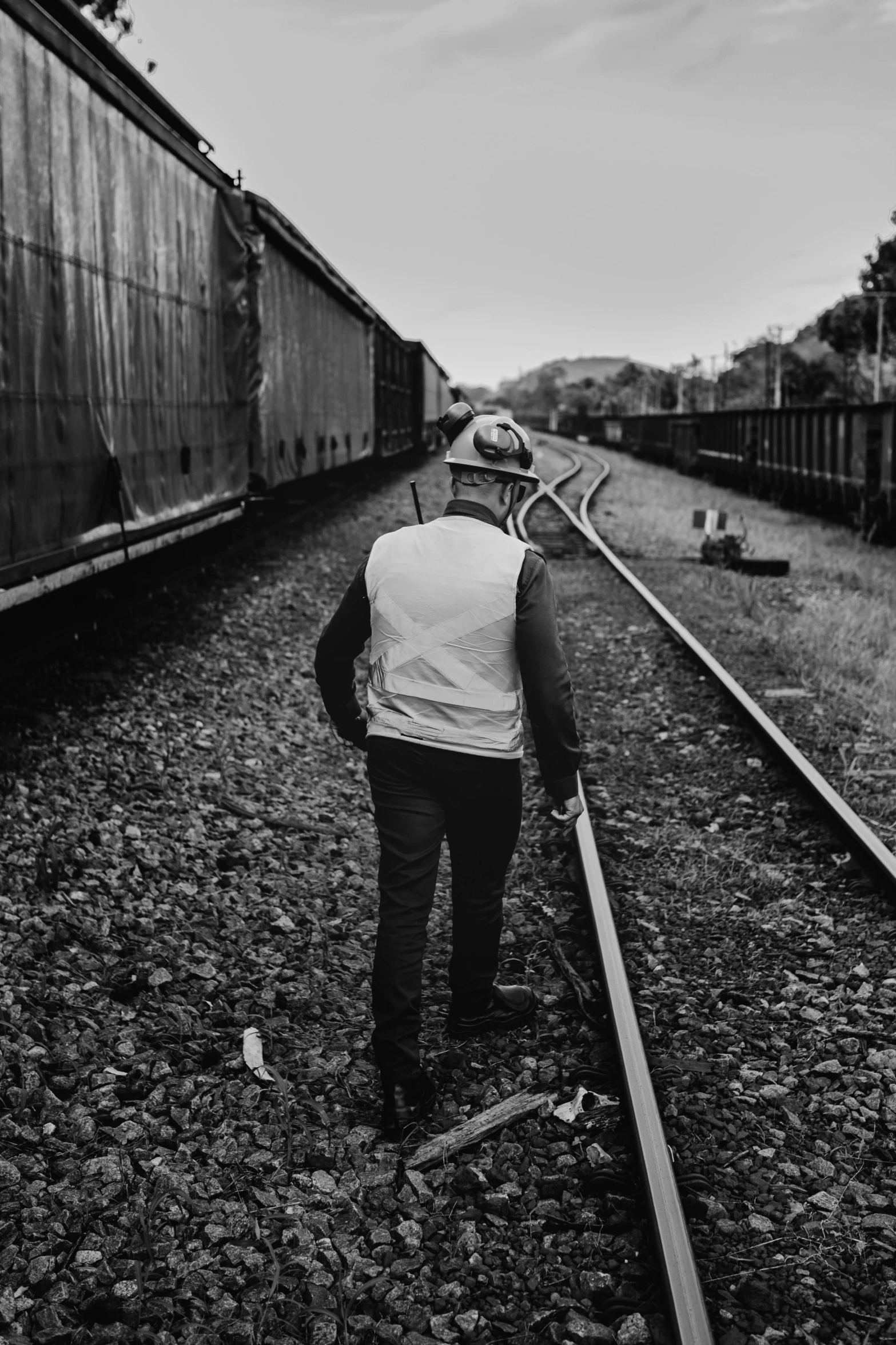 a man in a white vest walking along tracks