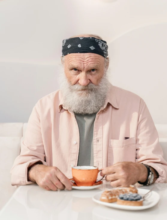 an old man with a grey beard eats in a restaurant