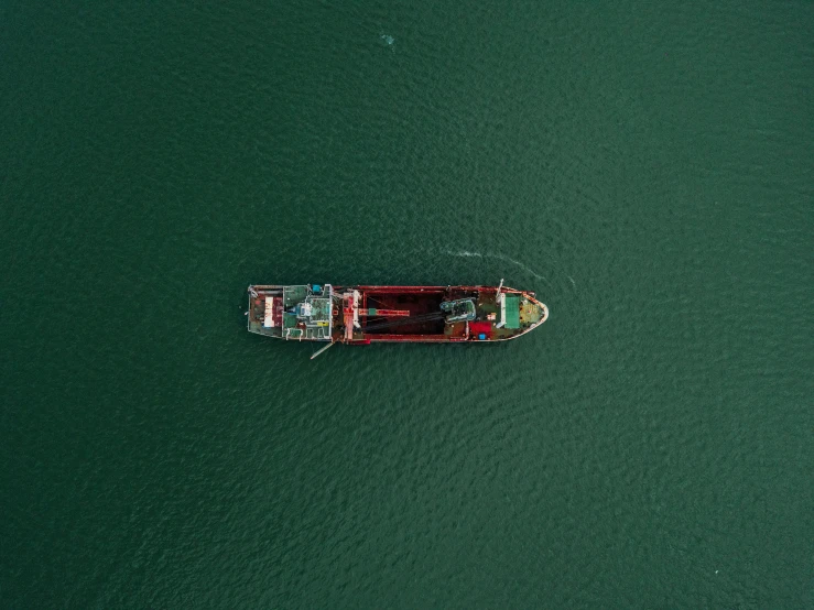 a long boat floats through the water from a high angle