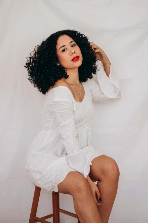 a young woman is sitting on a stool with long hair