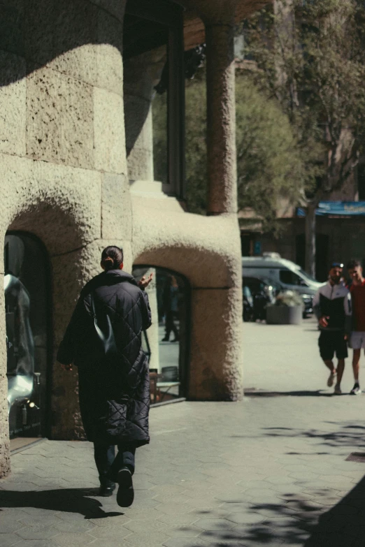 people walking down the sidewalk in an area with several pillars