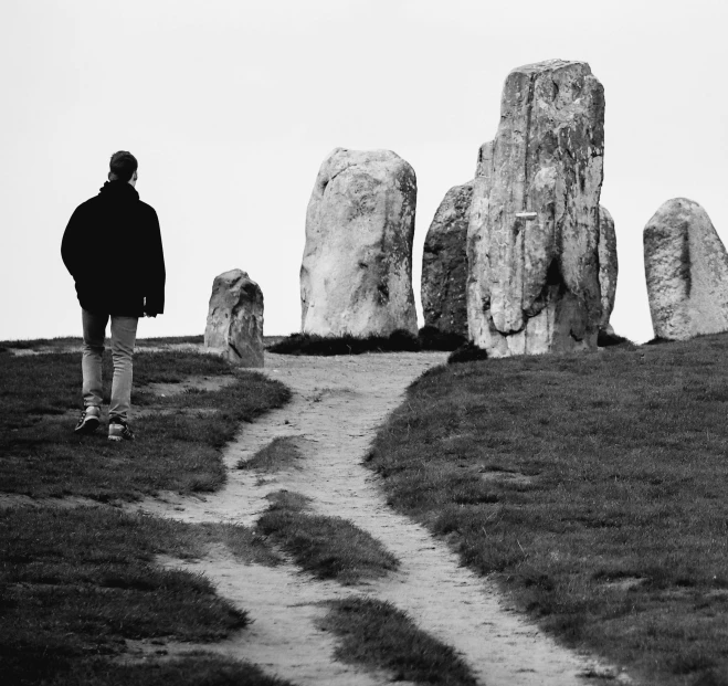 a person standing on top of a hill near large stones